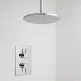 Chrome shower head and control panel on a tiled bathroom wall