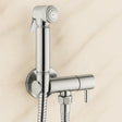 Chrome bathroom faucet with handheld shower head on a beige tiled wall background