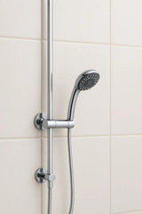 Chrome shower head and hose against a tiled bathroom wall