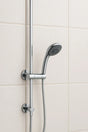 Chrome shower head and hose against a tiled bathroom wall