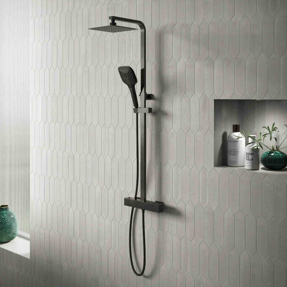 Black shower set mounted on a gray tiled wall with decorative elements.