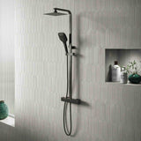 Black shower set mounted on a gray tiled wall with decorative elements.