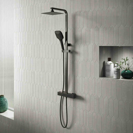 Black shower set mounted on a gray tiled wall with decorative elements.