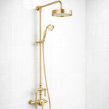 Gold shower set with rain shower head and handheld shower on a white tiled wall.