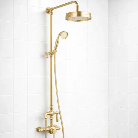 Gold shower set with rain shower head and handheld shower on a white tiled wall.
