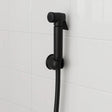 Black shower head and hose against a white tiled wall