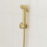 Gold handheld shower head on a tiled bathroom wall