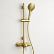 Gold shower head and control panel on a white tiled wall