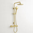 Gold shower set with handheld shower head and wall-mounted showerhead on a white tiled wall.