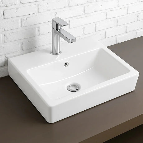 White ceramic sink with silver faucet against a white brick wall.