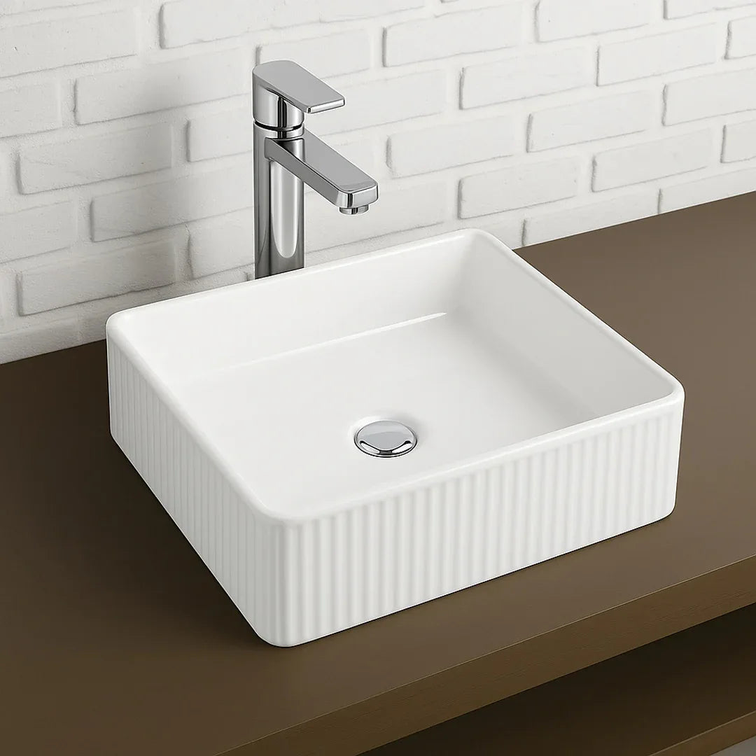 White rectangular sink with silver faucet against a white tiled wall.