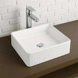 White rectangular sink with silver faucet against a white tiled wall.