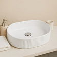 White ceramic sink on a bathroom counter with a beige wall background
