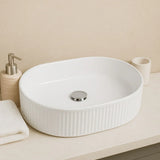 White ceramic sink on a bathroom counter with a beige wall background
