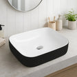 Rectangular black and white sink in a modern bathroom setting with a mirror and plants.