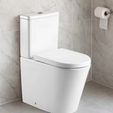 White toilet in a bathroom with gray tiled walls and a roll of toilet paper.