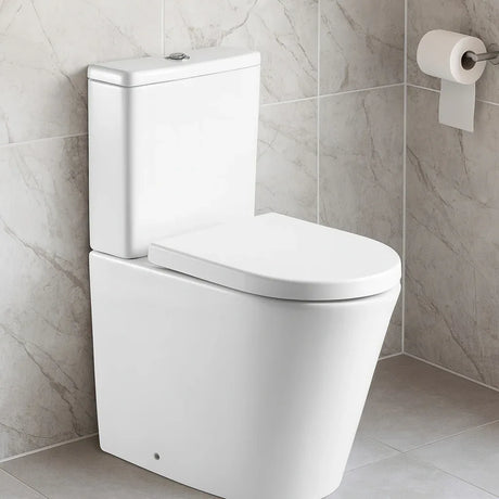 White toilet in a bathroom with gray tiled walls and a roll of toilet paper.