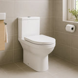 White toilet in a bathroom with beige tiles and a window.