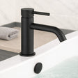 Black faucet on a bathroom sink with a towel in the background