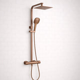 Rose gold shower system with rain shower head and handheld shower on a white tiled wall background