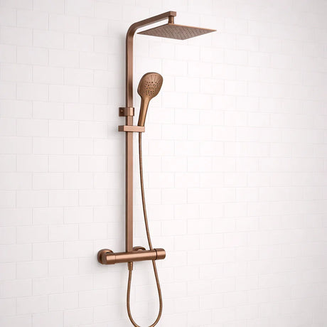 Rose gold shower system with rain shower head and handheld shower on a white tiled wall background