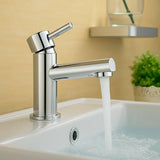 Chrome faucet with water flowing into a sink against a beige wall.