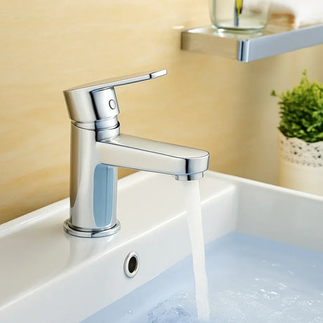 Chrome faucet on a sink with water flowing, blurred background