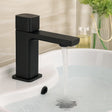 Black faucet on a sink with water flowing, blurred background
