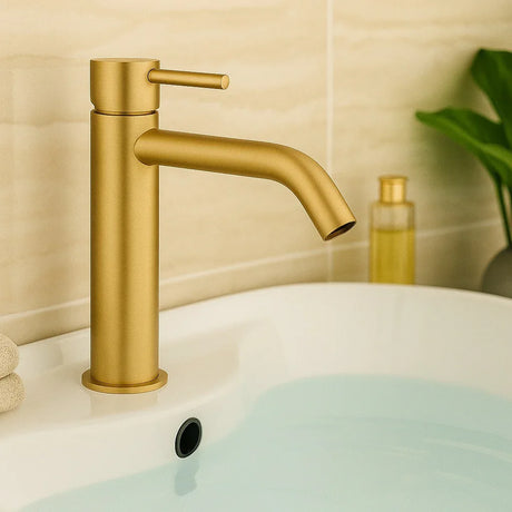 Gold faucet on a sink with a neutral background