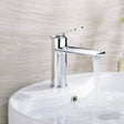 Chrome faucet on a white sink with water flowing, against a neutral wall.