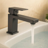Black faucet with water flowing into a sink against a beige wall.