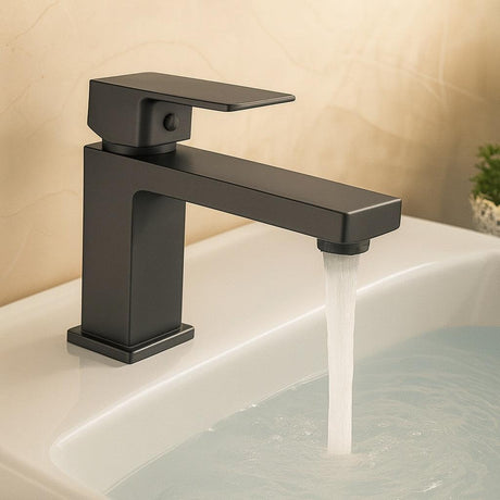Black faucet with water flowing into a sink against a beige wall.