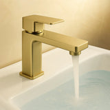 Gold faucet with water flowing into a sink against a beige background