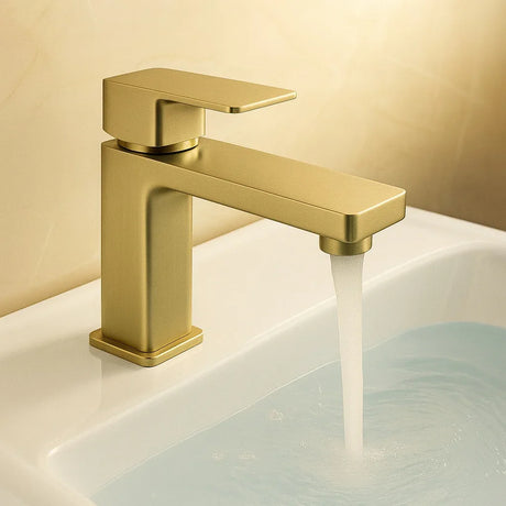 Gold faucet with water flowing into a sink against a beige background