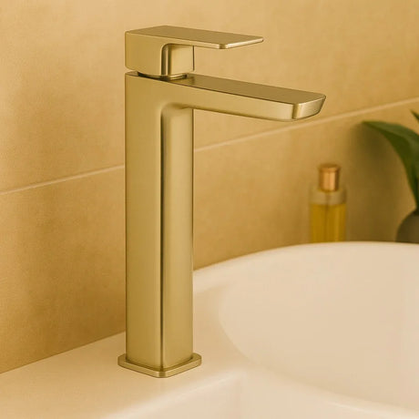 Gold faucet on a bathroom sink with a beige tiled wall in the background
