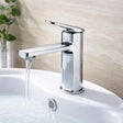 Chrome faucet on a sink with water flowing, against a neutral background