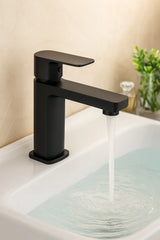 Black faucet on a sink with water flowing, against a neutral background.