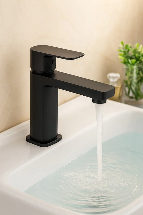 Black faucet on a sink with water flowing, against a neutral background.